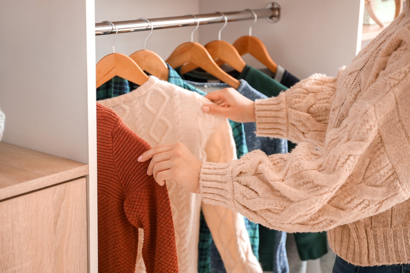 Woman Choosing Winter Clothes near Wardrobe