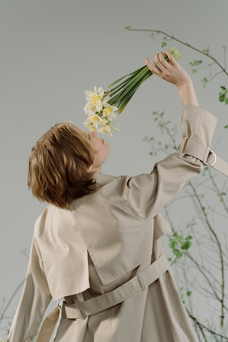 A Woman in Trench Coat Smelling Flowers